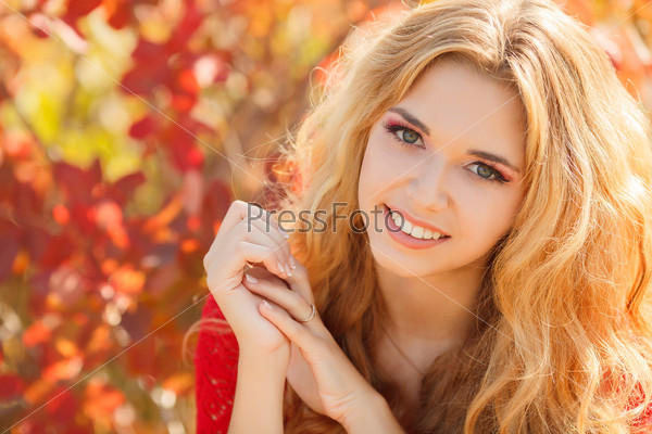 Young woman with autumn leaves in hand and fall yellow maple garden background. Autumn bright portrait.