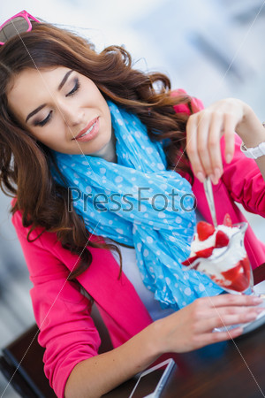 Beautiful sexy brunette woman in restaurant cafe with ice cream cake alluring woman in bright clothes and hairstyle and makeup eating dessert. Beauty fashion