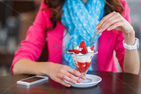 Beautiful sexy brunette woman in restaurant cafe with ice cream tiramisu cake. hairstyle and makeup eating dessert. Beauty fashion slim model
