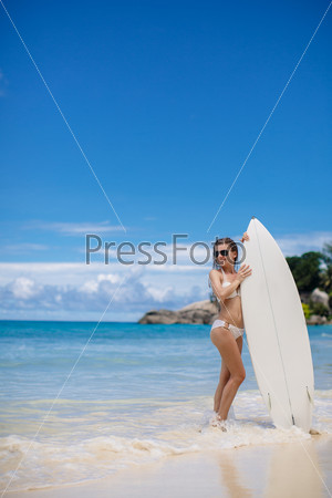 A beautiful young woman in a bikini with surfboard
