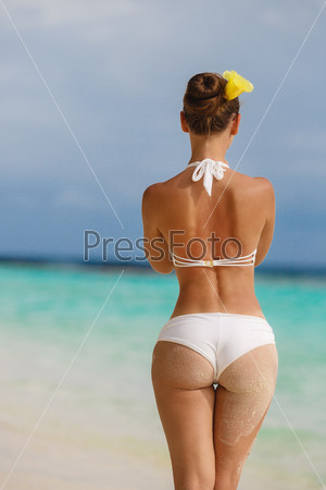 Sexy sandy woman buttocks on tropical beach background near ocean