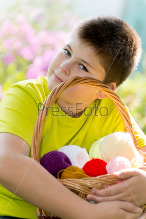 Teen boy with a wicker basket and balls of yarn