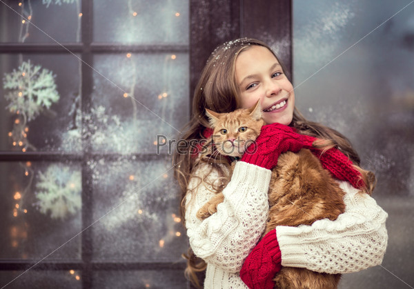 Child girl hugging her pet staying near her house decorated before Christmas