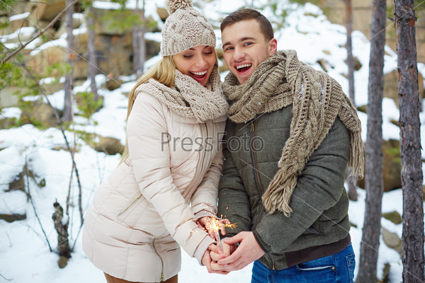 Happy couple with Bengal light celebrating holiday in winter forest