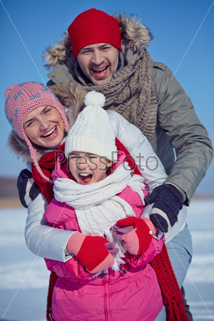 Joyful family of father, mother and daughter in winterwear