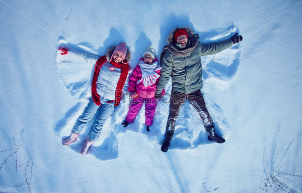 Young couple and cute little girl having fun in snowdrift, stock photo