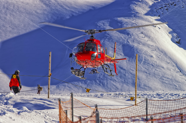 Red helicopter landing at swiss ski resort near Jungfrau mountai