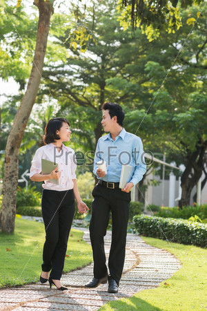 Vietnamese business couple talking while walking in the park