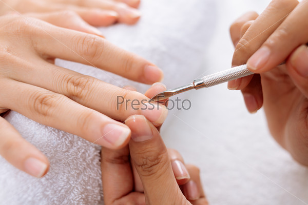 Close-up of manicurist removing cuticle from the nail