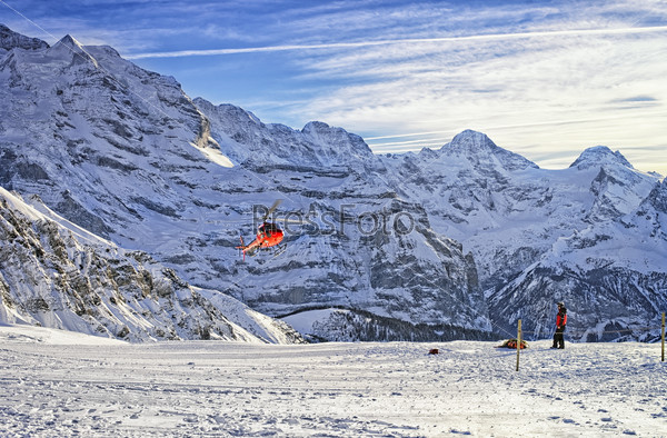 Red helicopter flying over swiss ski resort near Jungfrau mounta