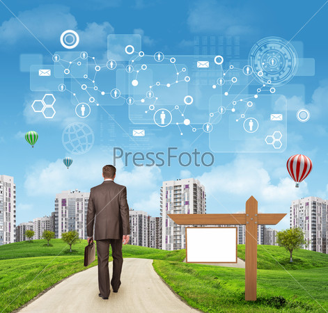 Businessman walking along road running through green hills towards city. Schemes, rectangles and other virtual items in sky