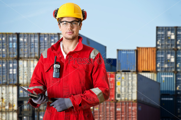 Logistics manager at a container transhipment plant, with an electronic tablet, and cb radio observing safety regulations