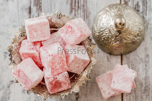 Rose flavoured Turkish delight in traditional silver bowl on wooden white background