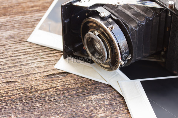 vintage  photo camera on pile of old instant photos on wooden background