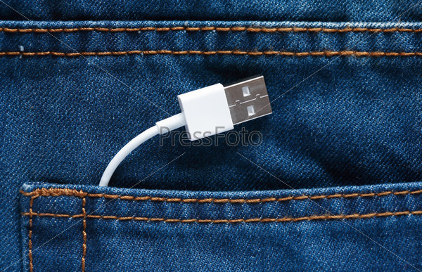 Modern technology. White USB-cable inside pocket of blue jeans