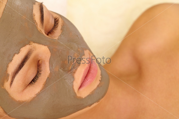 Relaxed woman having her face cleaned with clay mask