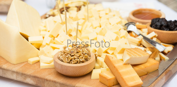 Cheese Plate with Dried Fruit, Nuts and Honey. Rustic decoration on a wooden plate.