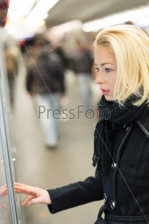Casually dressed woman wearing winter coat,buying metro ticket at the ticket vending machine. Urban transport, stock photo