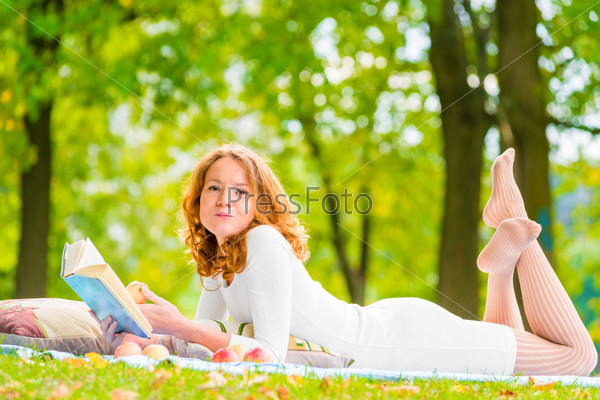 Romantic girl with a good book and a delicious apple in the park, stock photo