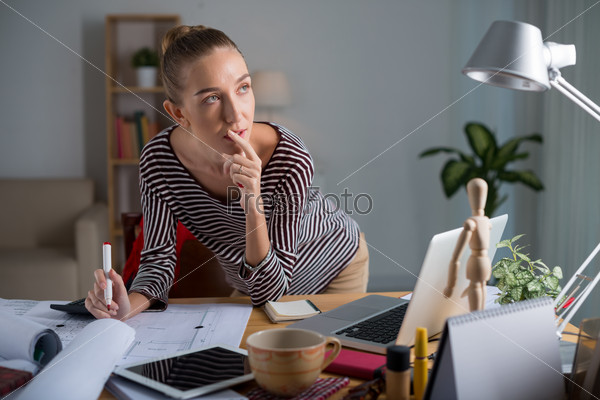 Pensive female designer working on housing project