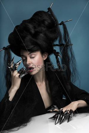 Gothic style shot of a woman with claw rings sitting at the table
