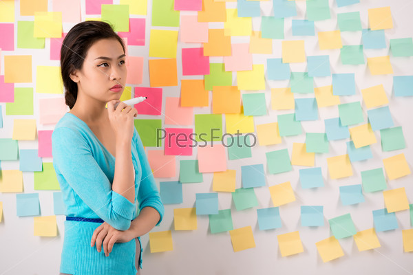 Pensive Vietnamese woman against wall covered with colorful stickers