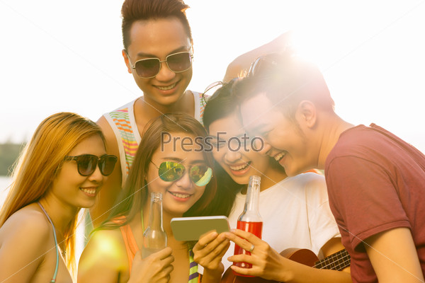 Group of laughing young people watching funny video or photo on the smartphone