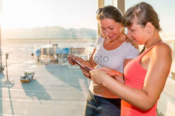 Two girls at the airport with tickets waiting for boarding