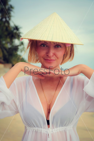Vietnamese girl and laughing on the beach trying on this hat.