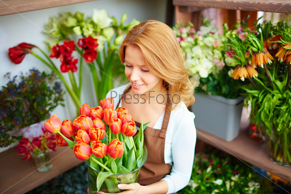 Young florist carrying vase of red tulips