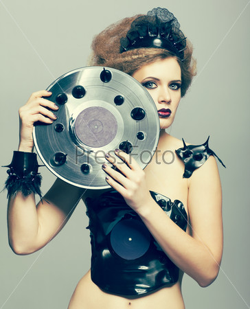 Woman in dress and diadem made of molten vinyl disk with record in hands
