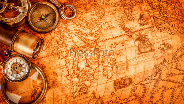 Vintage magnifying glass, compass, telescope and a pocket watch lying on an old map in 1565.