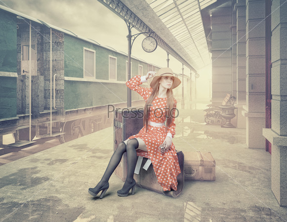 The girl sitting on the suitcase waiting at the retro railway station. Vintage color cards style