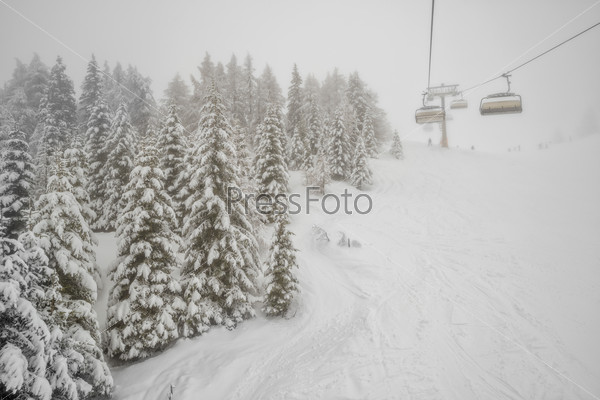 Chairlift in snowfall at alpine ski resort