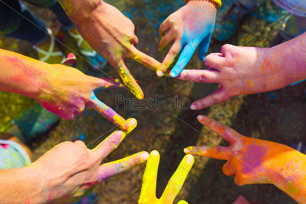 Friends putting their hands together in a sign of unity and teamwork. Holi colors festival. Friendship concept