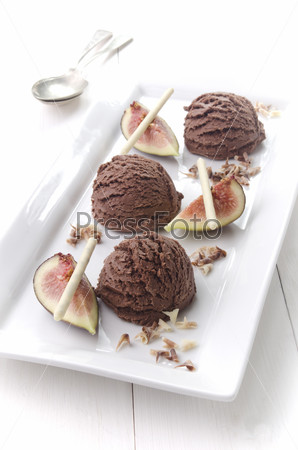 chocolate ice cream with fig, white chocolate sticks and chocolate curls on a white plate