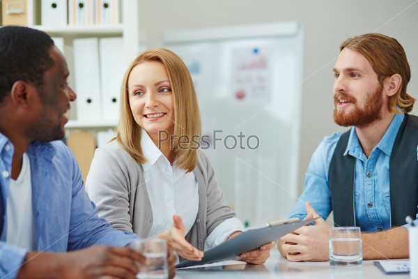 Pretty businesswoman explaining strategy to colleagues at meeting, stock photo