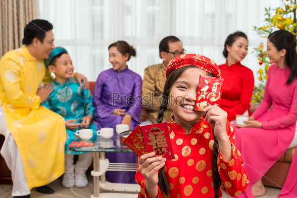 Little Vietnamese girl holding envelopes with money for Tet holiday