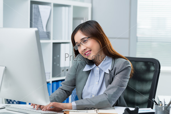 Young Asian business lady calling on the phone and working on computer