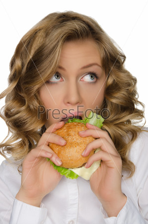 Young woman biting burger and looking away isolated on white