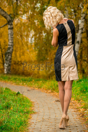 slim blonde walks alone in the park