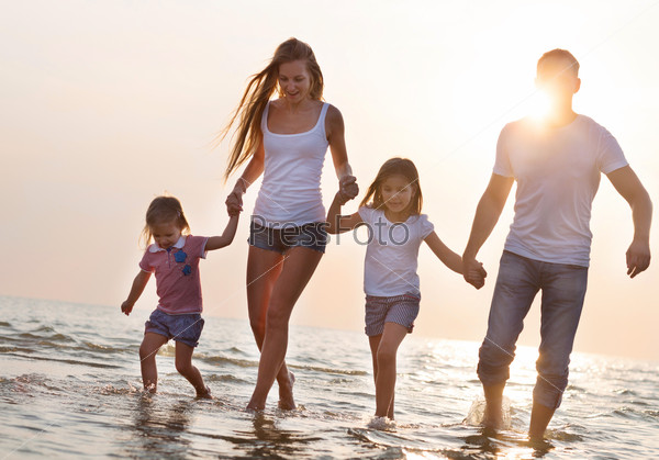 Молодая семья на пляже на закате
