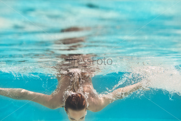 Молодая женщина под водой в бассейне