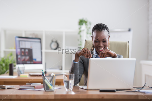 Pretty african business woman working on laptop in office