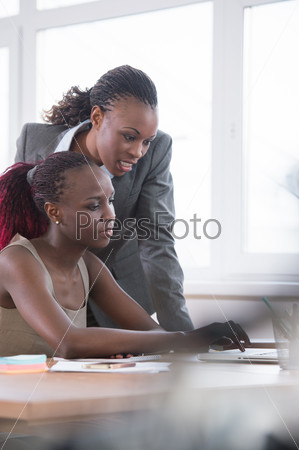 Young african business women in office working together on laptop