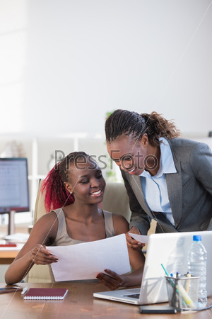 Two cheerful african american business women working at the office on a computer