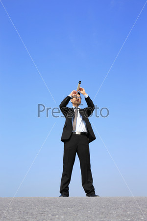 Businessman with telescope ( spyglass ) looking forward Prospects for future business with blue sky background, asian