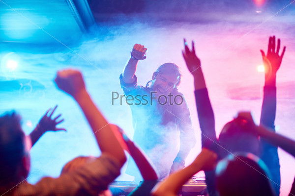Excited deejay encouraging dancing crowd in nightclub