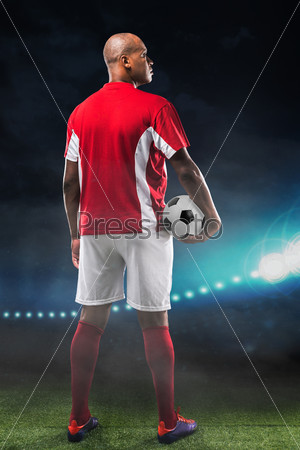 Rear view of soccer player with a ball standing at the field