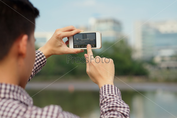 Man taking photo with his smartphone, view over the shoulder